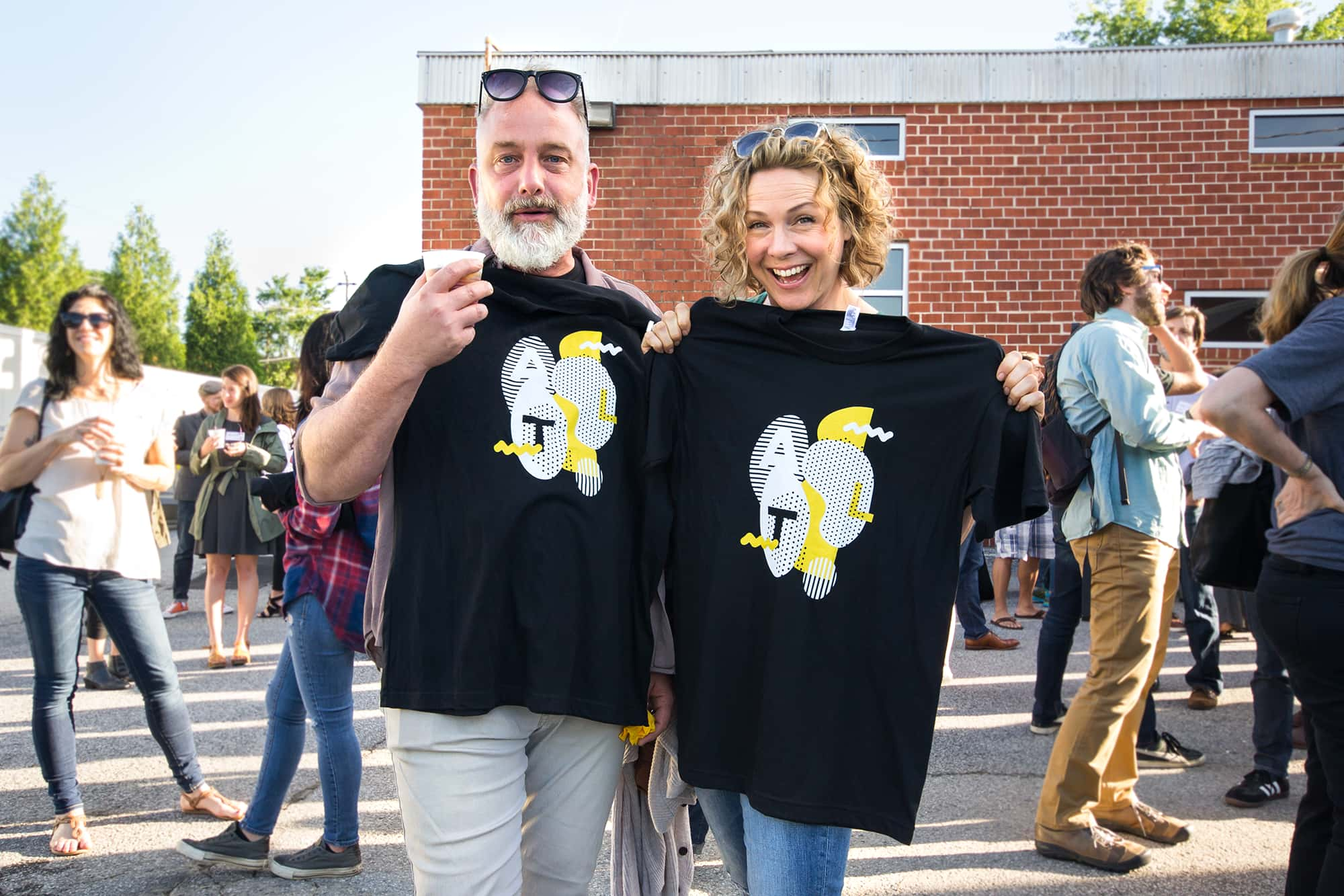 Two attendees posing while holding their event t-shirts.