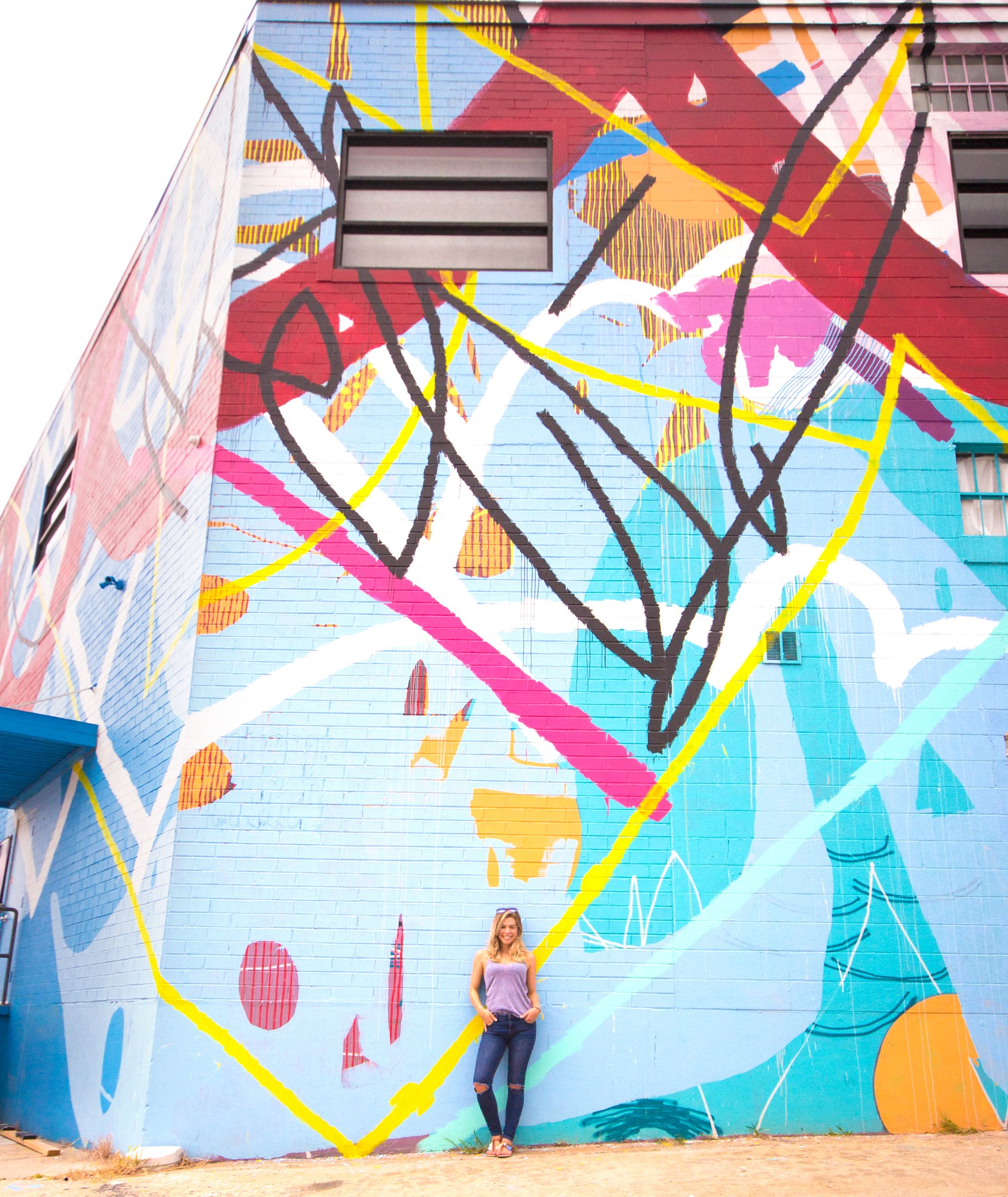 Posing in front of a large colorful mural.