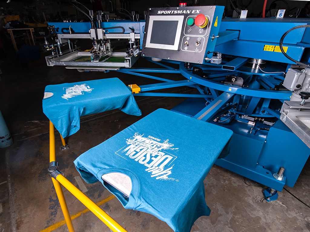 An automatic screen printing press printing an UberPrints themed t-shirt design.