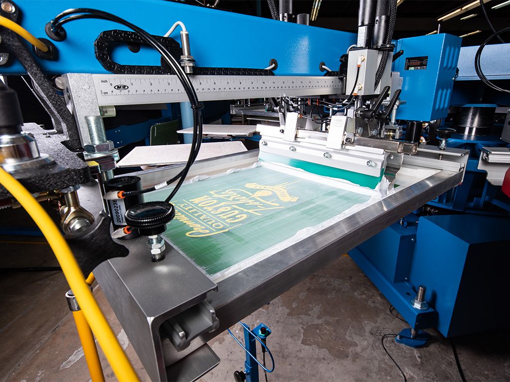 A detail image of the first print head on an automatic screen printing press.