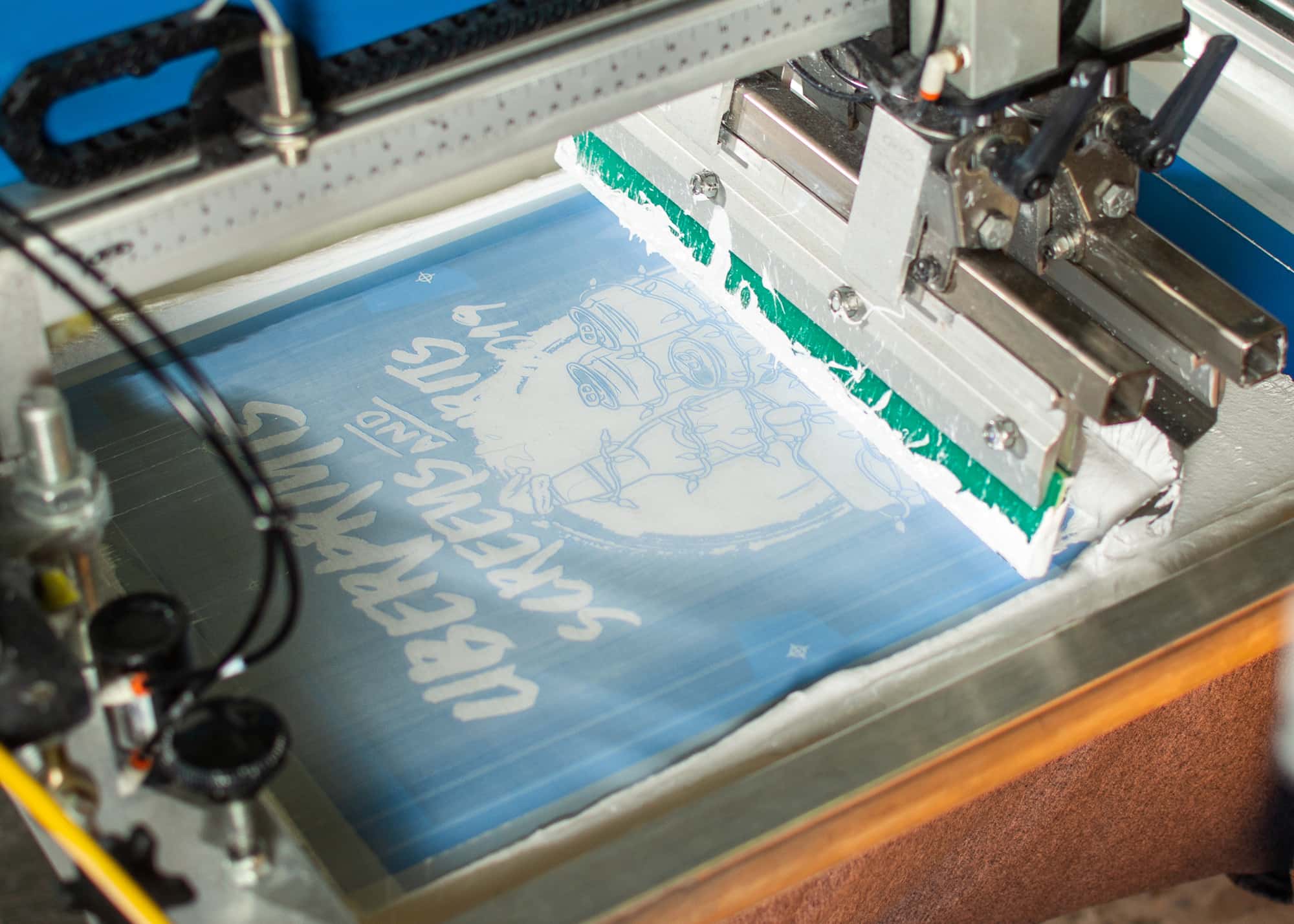 A detail shot of the underbase screen being printed for the Screens And Spirits t-shirt design.