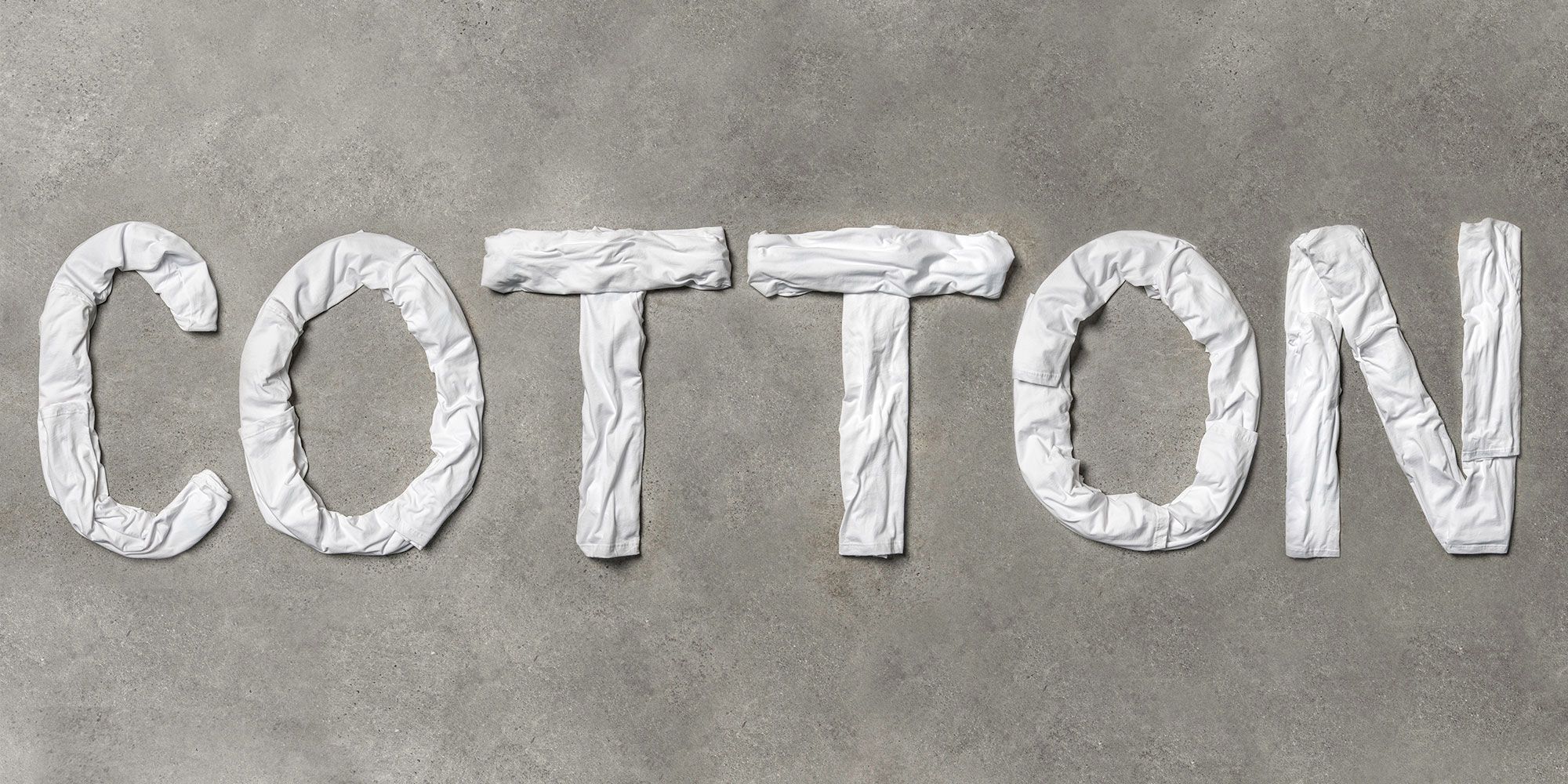 Flatlay shot of t-shirts spelling out the word cotton.