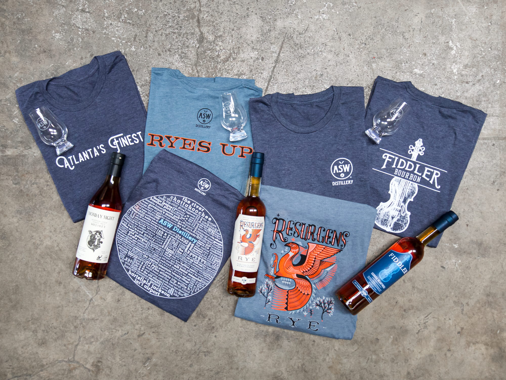 A topdown photo showing a variety of folded custom t-shirts for a distillery.