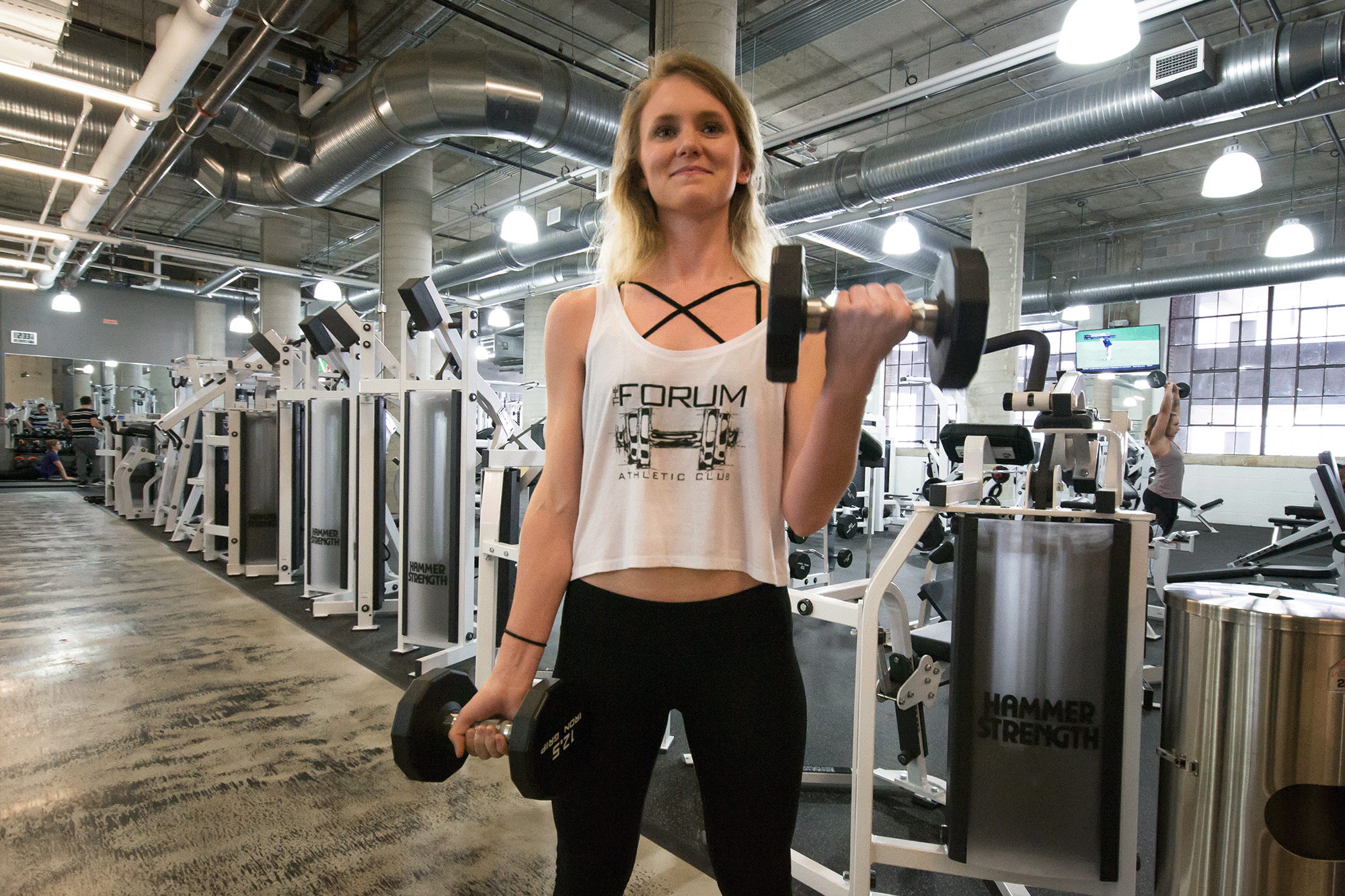 An animated gif of a person in a gym lifting weights while wearing a custom tank top for their gym.