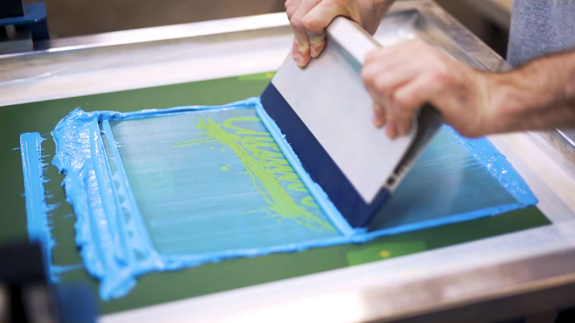 A screen printer laying down one color of a two color t-shirt design.