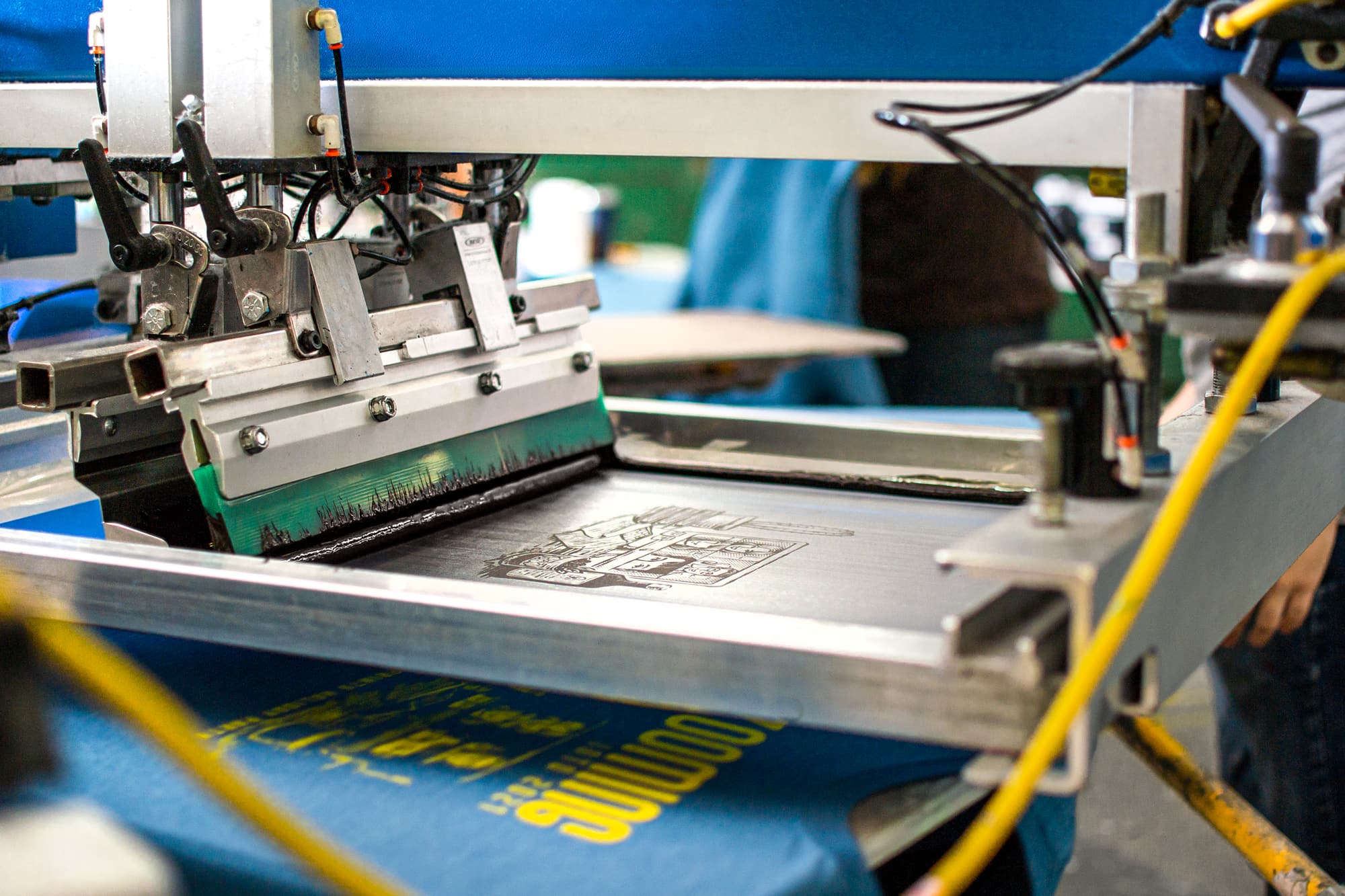 Image from the UberPrints warehouse showing a design being screen printed onto a shirt.