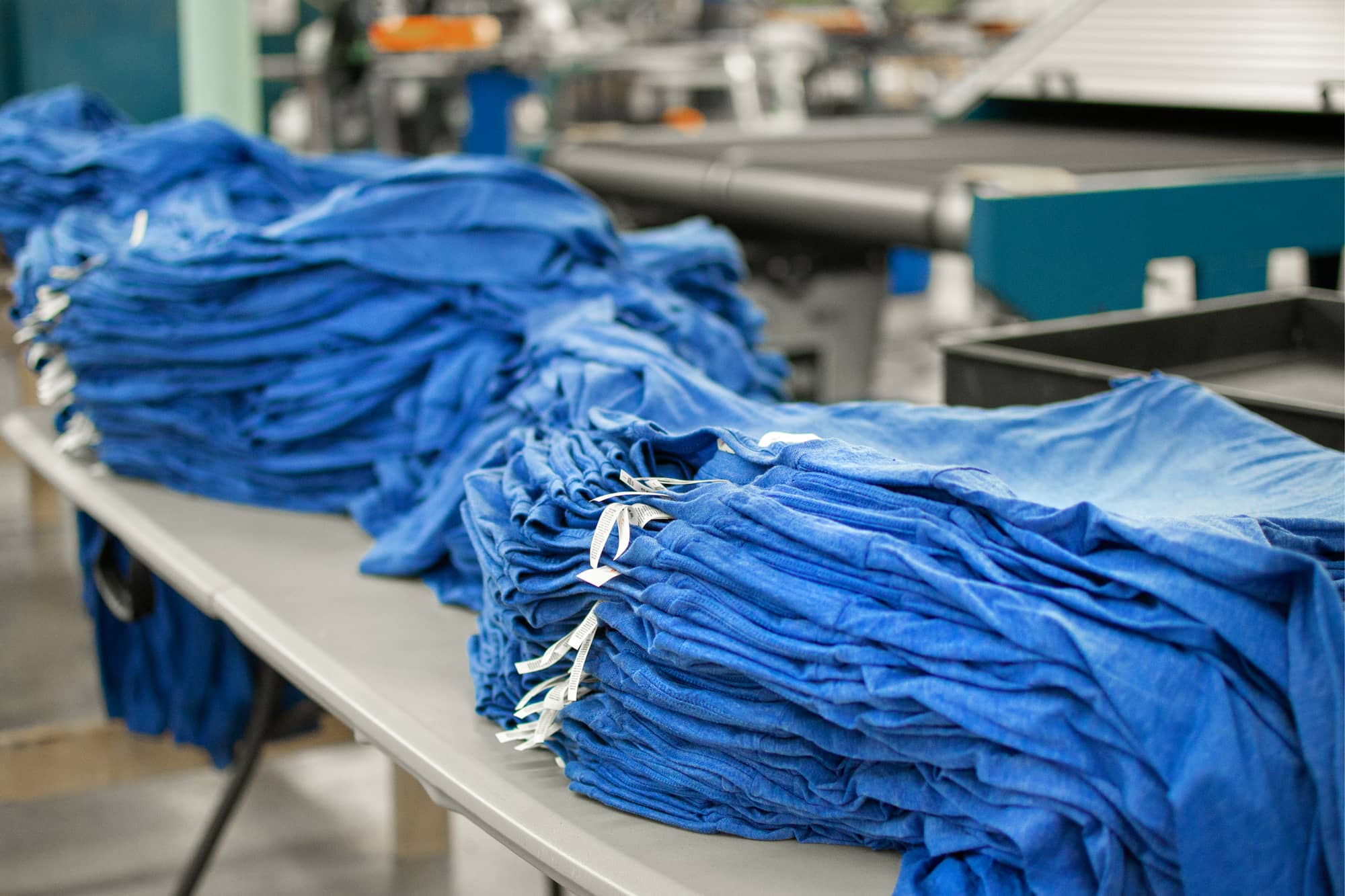 An image showing a stack of t-shirts ready to be screen printed for a bulk order.