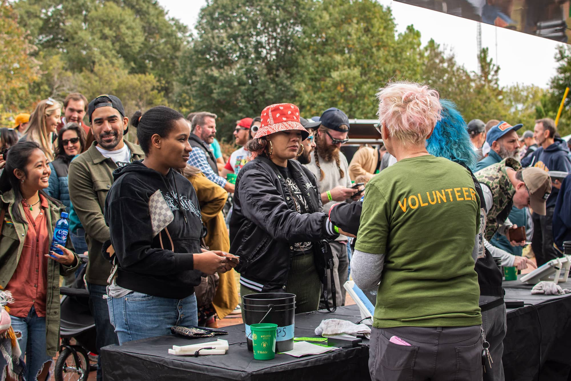 Candid image of a person wearing a volunteer t-shirt serving a long line of customers at an event.