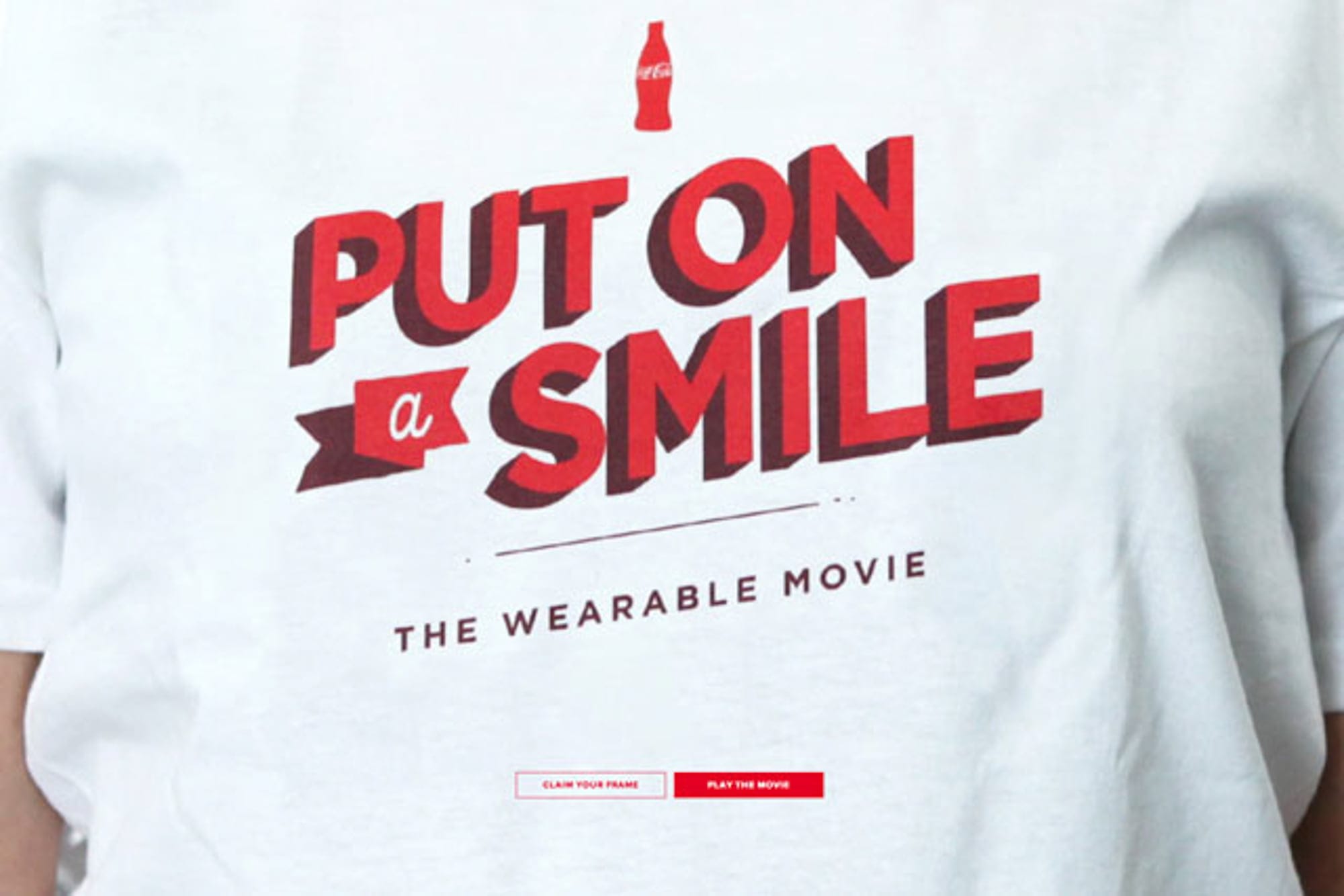 A closeup of a person wearing a white shirt that says "put a smile on - the wearable movie"