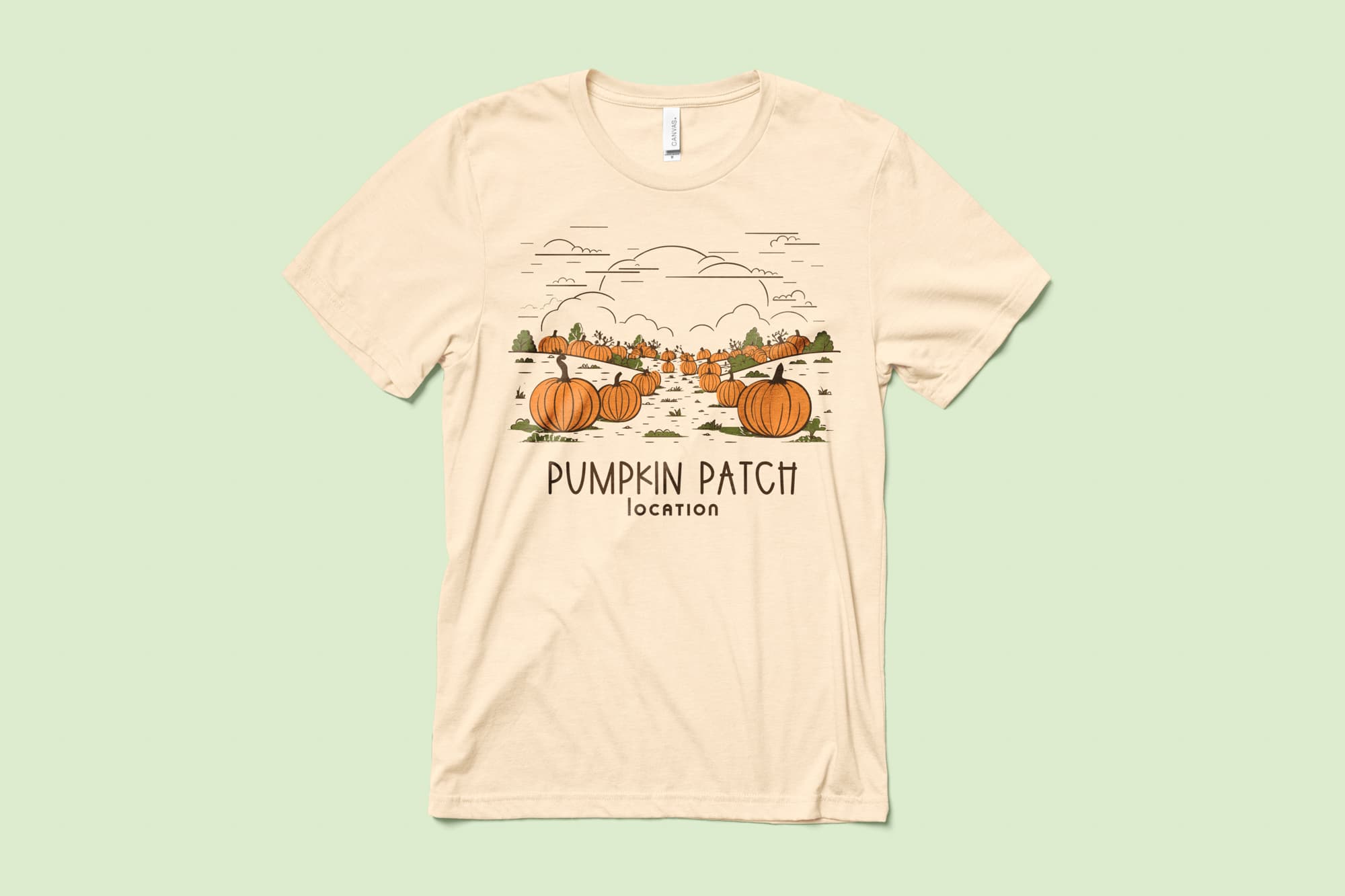 Image of a cream color t-shirt with a customizable halloween design of a pumpkin patch.