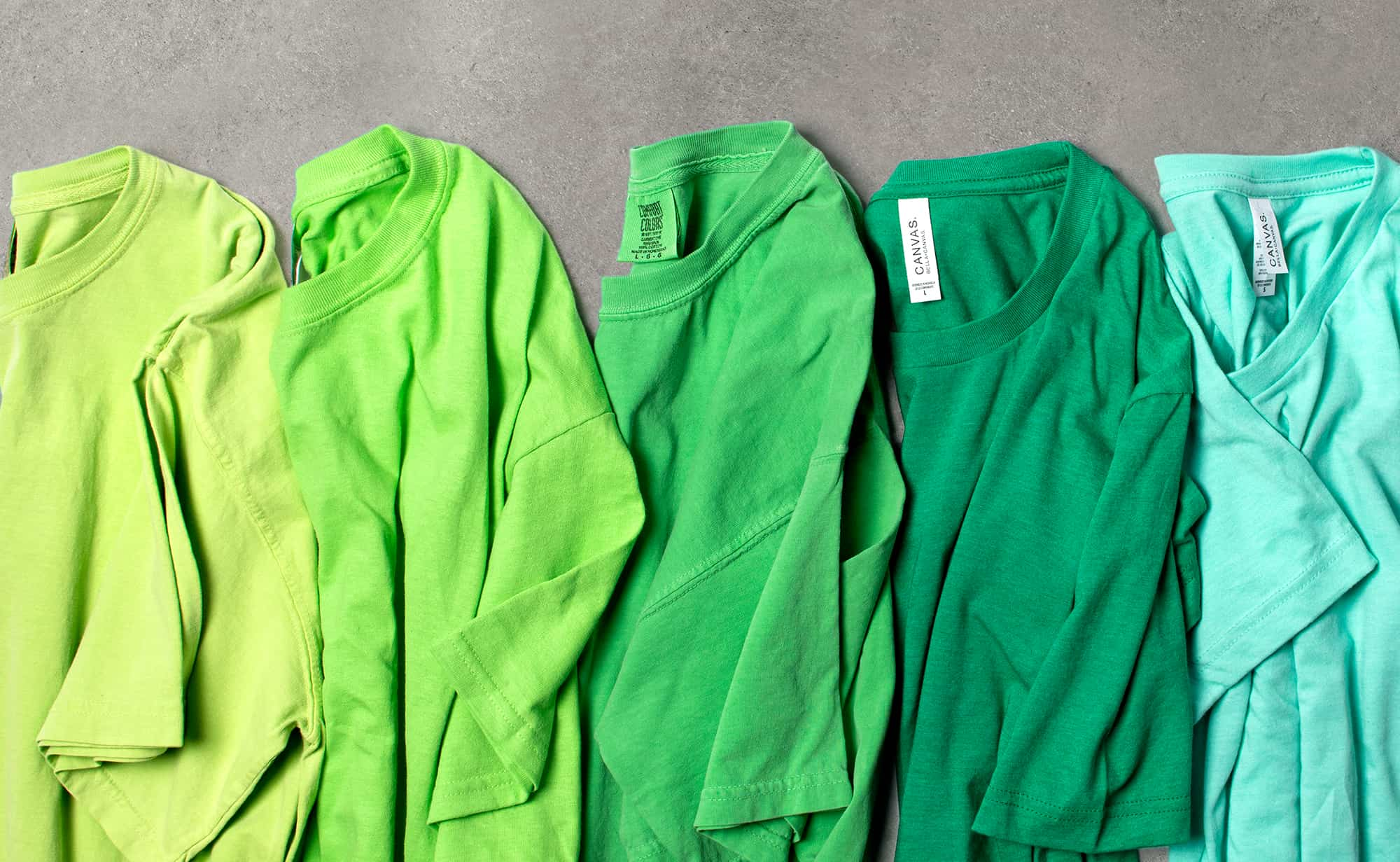 Image of partially folded green shirts in a row.