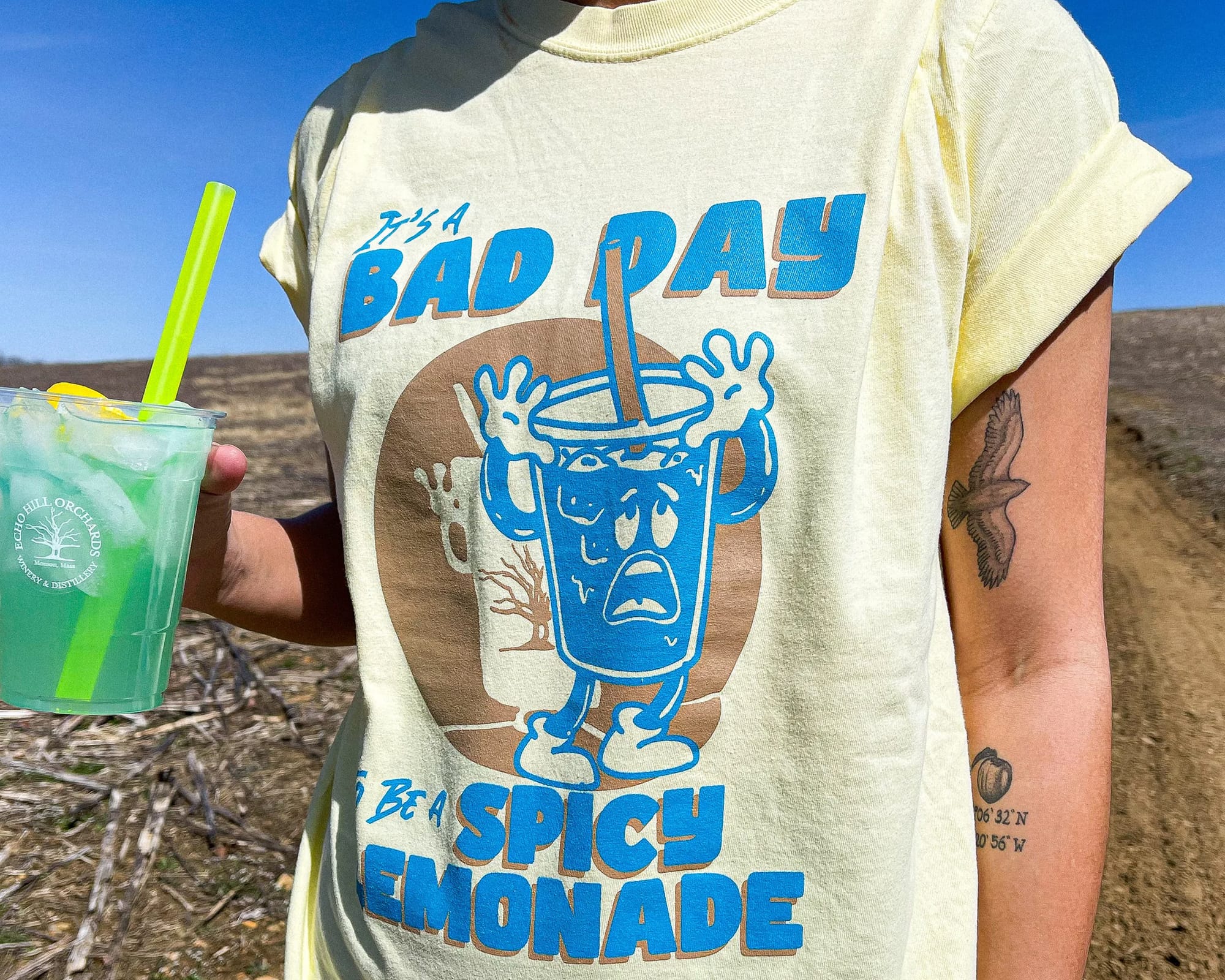 Image of a person holding a lemonade while wearing a t-shirt that says "It's a bad day to be a spicy lemonade"