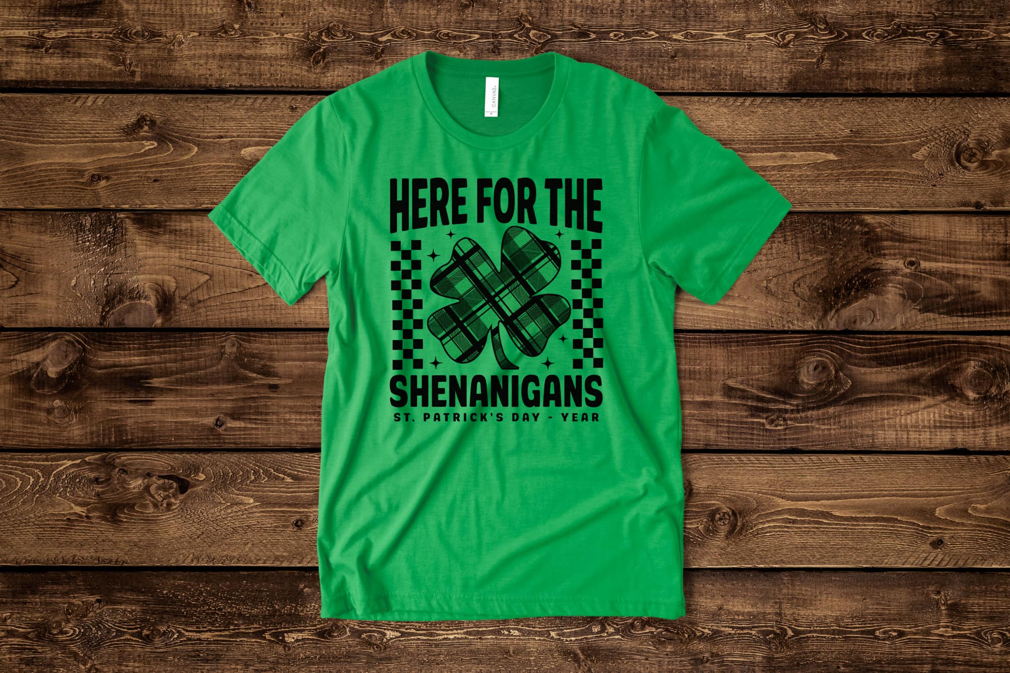 image of a flat green shirt with a customizable st. Patrick day design with a shamrock and text that says "here for the shenanigans"