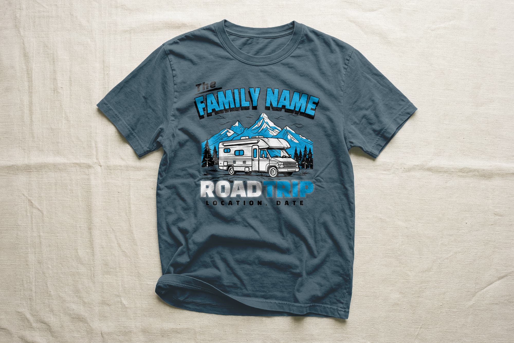 Gray t-shirt with a graphic of an RV in front of snowy mountains and pine trees. Text reads "Family Name Road Trip" with placeholders for location and date. Casual and adventurous theme.